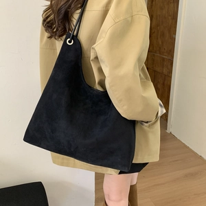 Side view of large black suede tote bag shown on a model for everyday city commuting
