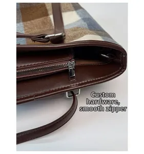 Detailed view of the smooth custom zipper and leather trim on the plaid tote bag