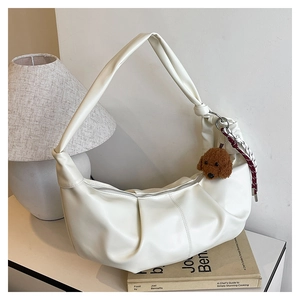 Detail of white pleated crescent bag with cute bear charm and woven rope decoration