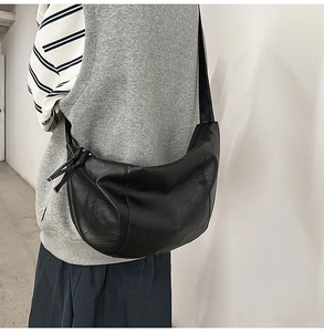 Vue détaillée du grand sac bandoulière en cuir noir en forme de croissant et son grain