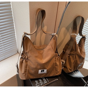 Dettaglio della borsa a tracolla marrone con tasche laterali a coulisse e logo patch