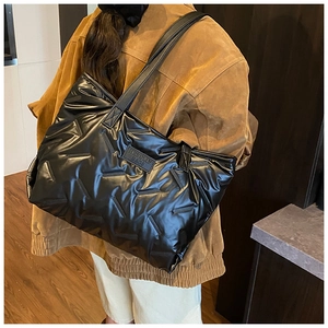 Detail of the black quilted puffer tote bag featuring an embossed brand leather patch