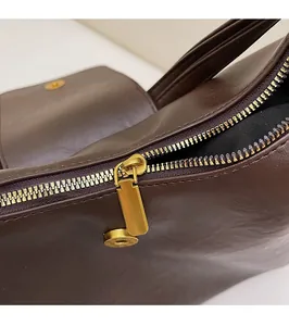 Detail of premium golden metal zipper and smooth dark brown leather on tote bag