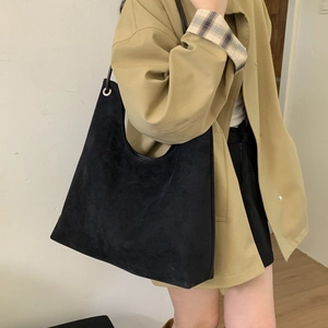 Close-up of a large black matte leather shoulder bag worn by a model for daily commute