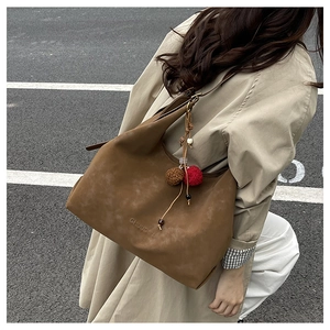 Détail du grand sac cabas marron en suédine avec son pendentif décoratif à pompons soigné