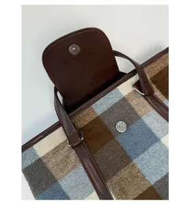 Detail of magnetic snap closure on vintage plaid wool tote bag with brown leather accents