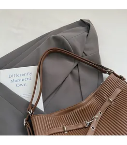 Close-up of pleated dark brown leather shoulder bag with decorative metal eyelet straps