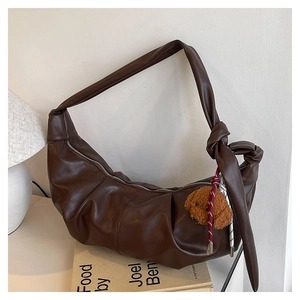 Detailed view of dark brown crescent bag with soft pleats and teddy bear charm