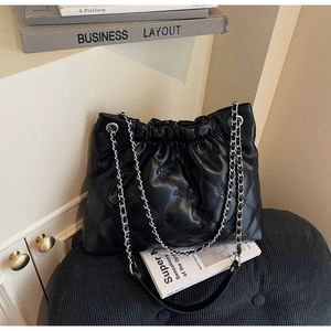 Gros plan sur un sac seau matelassé noir avec bandoulière chaîne et cordon serrage