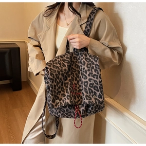 Leopard print canvas backpack with red embroidery and buckle detail shown on a model