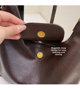 Detail of dark brown leather tote featuring a magnetic gold buckle for easy closure
