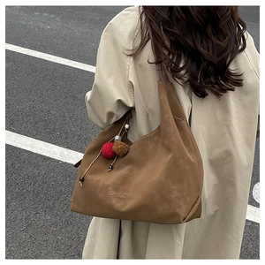 Détail d'un grand cabas en daim marron avec charm en peluche et logo en relief chic