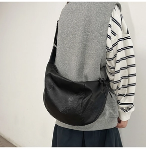 Détail d'un grand sac besace en similicuir noir avec des textures plissées douces