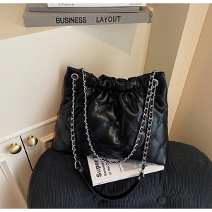 Détail d'un sac seau noir matelassé avec motifs floraux et bandoulière en chaîne