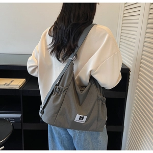 Dettaglio della borsa hobo in tela grigio scuro con logo orso e chiusura con coulisse laterale