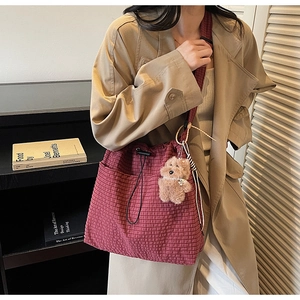 Detail of burgundy checkered drawstring bucket bag with a cute plush dog charm