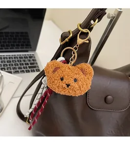Detail of cute bear plush charm with gold metal clasp on a leather shoulder bag