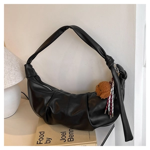 Detail of black pleated crescent bag with wide strap, silver zipper and dog charm