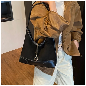 Detail of black suede tote bag with contrast white stitching and metal ring buckle closure