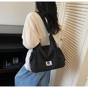 Dettaglio della borsa a tracolla in nylon nero plissettato con logo e coulisse