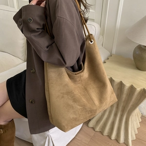 Close-up of brown suede tote bag with slim leather straps in a cozy setting