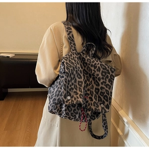 Detail of leopard print backpack with drawstring closure and red embroidery on flap