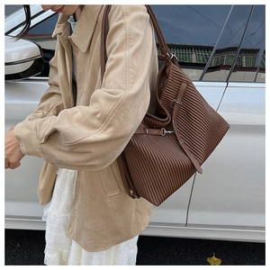 Detail view of large dark brown tote bag with pleated texture and adjustable strap