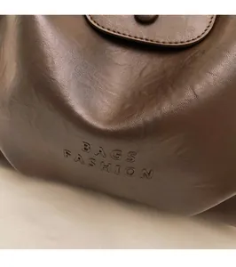 Close-up of the dark brown leather texture with embossed BAGS FASHION text detail