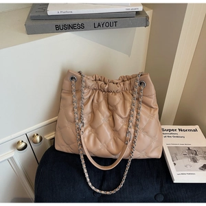 Détail du sac seau matelassé beige avec bandoulière chaîne et texture cuir raffinée