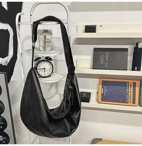 Grand sac bandoulière hobo noir en similicuir texturé suspendu sur un support en métal