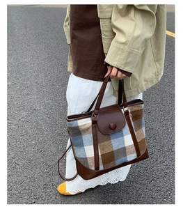 Detail view of vintage plaid tote bag with brown leather handles and textured fabric finish