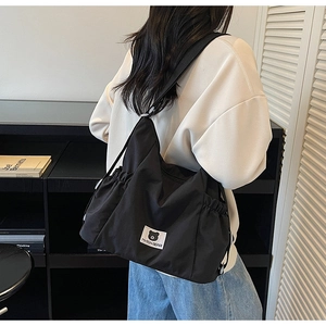 Detail showing the pleated nylon texture and bear logo patch on the large black tote bag