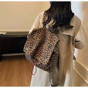 Fashionable leopard print backpack featuring red embroidery and drawstring closure detail