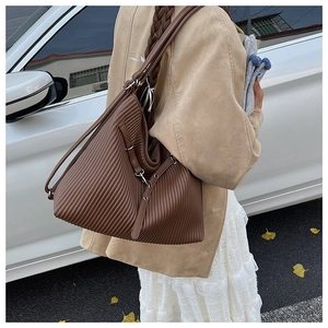Detail of vintage brown pleated tote bag with metal buckle on a shoulder strap