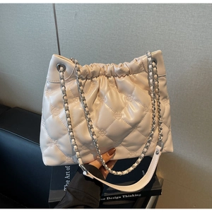 Détail du sac seau matelassé beige avec chaîne argentée et fermeture à cordon