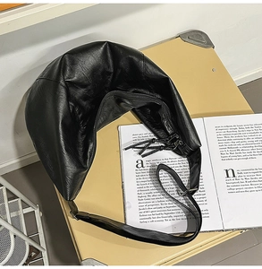 Vue détaillée du sac bandoulière croissant noir avec texture litchi et plis