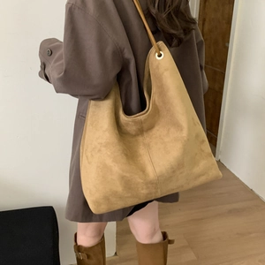 Detail of soft khaki suede hobo tote bag worn with a long winter coat for a chic look
