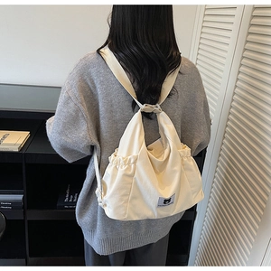 Dettaglio della borsa in tela bianco sporco con chiusura a coulisse e patch logo