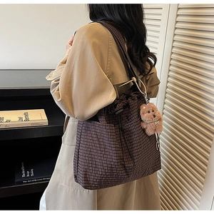 Detail of dark brown checkered bucket bag with drawstring and cute plush bear charm