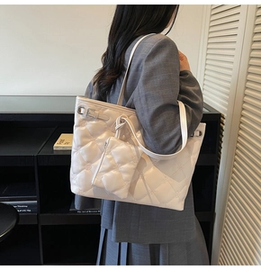 Détail du sac cabas beige matelassé avec breloques de fleurs porté par un mannequin