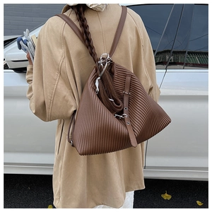 Detail of vintage pleated dark brown leather backpack with woven strap and metal hardware