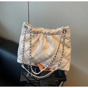 Détail du sac seau matelassé crème avec broderie florale et bandoulière chaîne