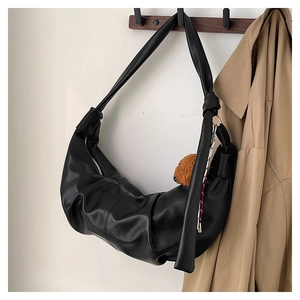 Detail of black pleated hobo bag featuring a cute bear charm and soft PU leather texture