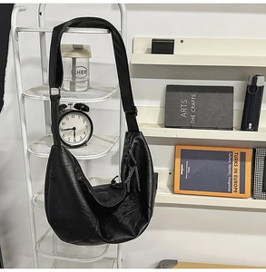 Détail du sac demi-lune en cuir PU noir avec une longue tirette de fermeture à franges