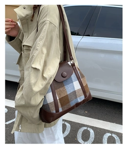 Detailed view of vintage plaid tote bag with brown leather trim carried by a model