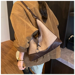Close-up of hobo bag showing suede texture, leather trim, and polished metal hardware
