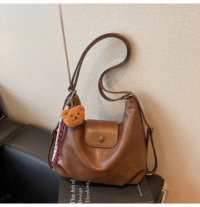 Detail of vintage brown leather shoulder bag with bear pendant and fashion logo