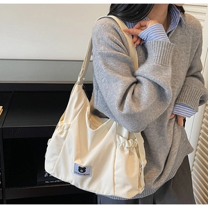 Dettaglio della borsa tote in tela crema con patch orso e tasche laterali a coulisse