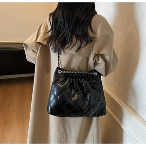 Détail du sac seau noir matelassé avec bandoulière chaîne montrant texture et style