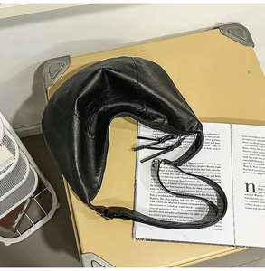 Vue détaillée du grand sac hobo noir en cuir posé sur une valise vintage et un magazine